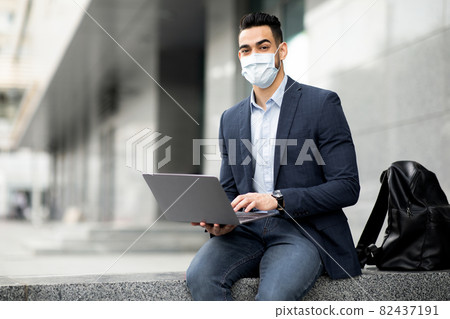 Arab guy entrepreneur sitting on the street, using laptop 82437191