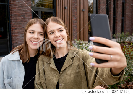 Two cute girls with blond hair making selfie outdoors 82437194