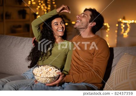 Couple Having Fun Eating Popcorn Flirting During Date At Home Couple Having Fun Eating Popcorn Flirting During Date At Home 82437359