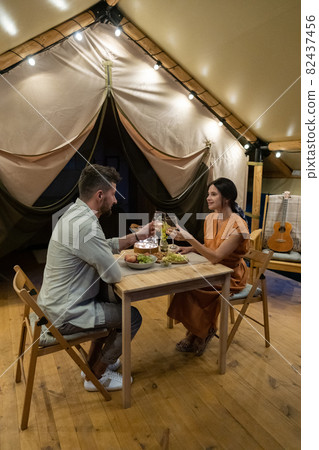 Young amorous couple cheering up with glasses of wine by romantic dinner 82437456