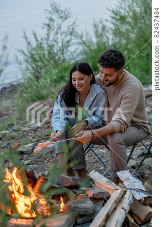 Happy young couple spending time by campfire 82437484