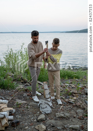 Father ans son with axe chopping firewood together Father ans son with axe chopping firewood together 82437553