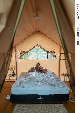 Young amorous couple resting in bed under white blanket Young amorous couple resting in bed under white blanket 82437657
