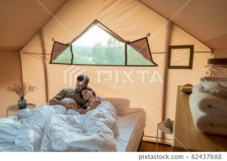 Affectionate couple looking at scenery around their glamping tent Affectionate couple looking at scenery around their glamping tent 82437688