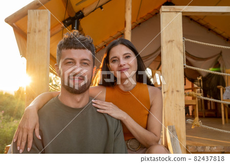 Happy young woman embracing her husband while both enjoying summer rest Happy young woman embracing her husband while both enjoying summer rest 82437818