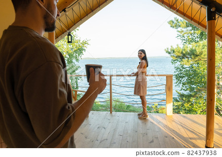 Young woman looking at her husband with cup of tea Young woman looking at her husband with cup of tea 82437938