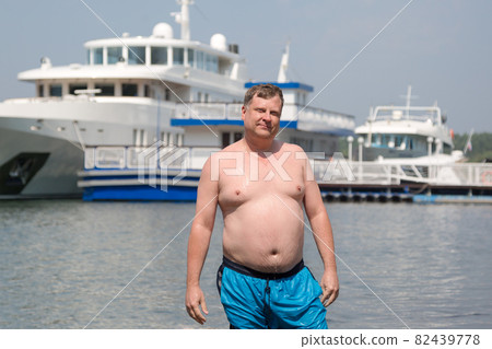 A young oligarch swims in the sea against the background of his own yacht 82439778