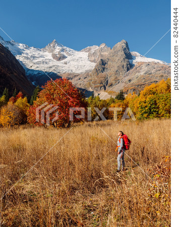 Woman with backpack in the autumnal mountains. Mountain with ice glacier and hiker tourist 82440444