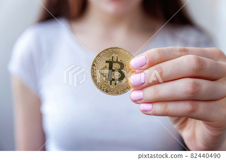 Cryptocurrency golden bitcoin coin in woman hand. Electronic virtual money for web banking and international network payment. Symbol of crypto currency. 82440490