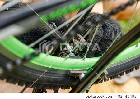 Bike mechanic man repairs bicycle in bicycle repair shop, outdoor. Hand of cyclist bicyclist examines, fixes modern cycle transmission system. Bike maintenance, sport shop concept. Bike mechanic man repairs bicycle in bicycle repair shop, outdoor. Hand of cyclist bicyclist examines, fixes modern cycle transmission system. Bike maintenance, sport shop concept. 82440492
