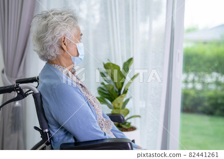 An elderly woman sitting on wheelchair looking out the window for waiting someone. Sadly, melancholy and depressed. 82441261