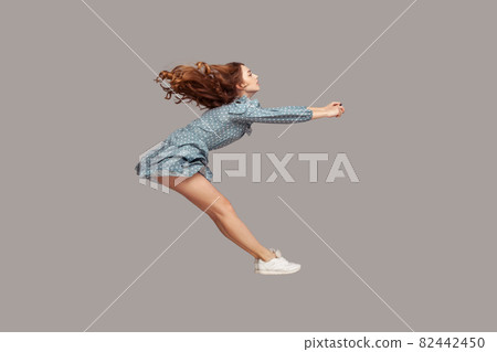 Side view girl rushing at full speed accelerate, steering driving fast and levitating in air. Model flying rapidly 82442450