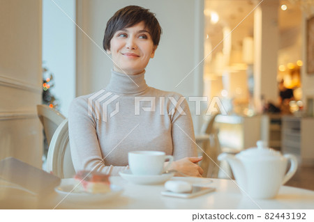 pretty young smiling woman sitting in the cafe with a cup of tea 82443192