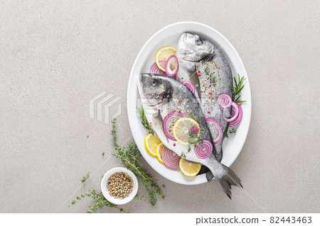 Fresh whole dorada fish and ingredients for cooking. Raw sea bream with spices on white background. Healthy food, diet. Top view with copy space. Fresh whole dorada fish and ingredients for cooking. Raw sea bream with spices on white background. Healthy food, diet. Top view with copy space. 82443463