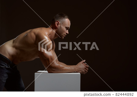Male muscular athlete poses at the cube in studio 82444892