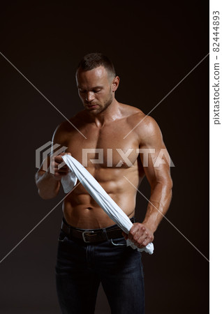 Male muscular athlete holds his shirt in hands 82444893