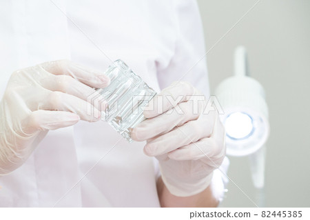 Doctor wearing medical gloves holding a pack of rectal or vaginal suppositories 82445385