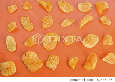 Potato chips or crisps on orange background. Movie background. Top view or flat lay. Potato chips on a pastel orange background, top view. Cinema Concept. Flat lay Potato chips or crisps on orange background. Movie background. Top view or flat lay. Potato chips on a pastel orange background, top view. Cinema Concept. Flat lay 82446076