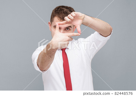 man looking through photo frame made of hands, focusing and cropping image. 82448576