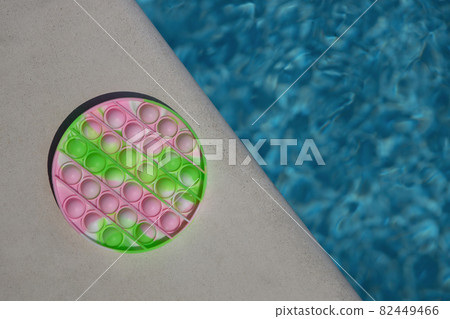 Anti-stress toy pop it, simple dimple on side of pool, copy space. Concept trendy summer entertainment for fidget children, sensory toys for development of fine motor skills, stress relieving 82449466