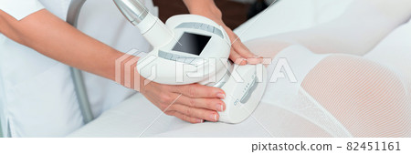 Woman in special white suit getting anti cellulite massage in a spa salon. LPG, and body contouring treatment in clinic. Woman in special white suit getting anti cellulite massage in a spa salon. LPG, and body contouring treatment in clinic. 82451161