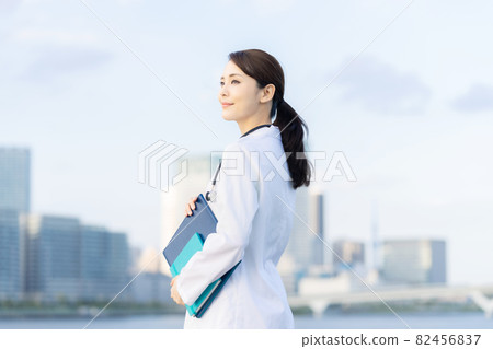 一位身穿白大褂的女醫生站在城市前，一位科學家 82456837