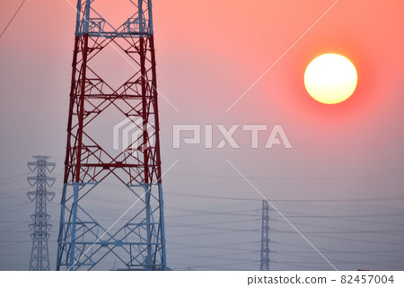 A round sunset and a silhouette of a steel tower in the madder red sky at sunset A round sunset and a silhouette of a steel tower in the madder red sky at sunset 82457004