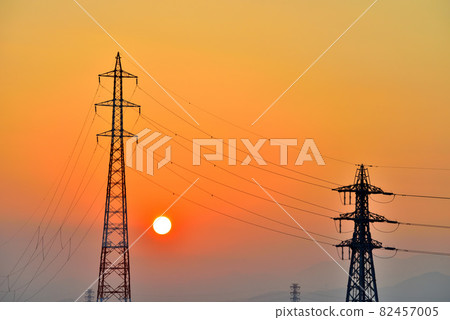 A round sunset and a silhouette of a steel tower in the madder red sky at sunset A round sunset and a silhouette of a steel tower in the madder red sky at sunset 82457005