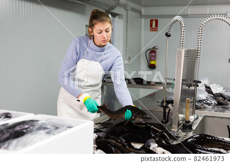 Woman preparing fish for packaging 82461973