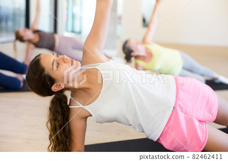 Young female performing set of exercises in pilates studio 82462411