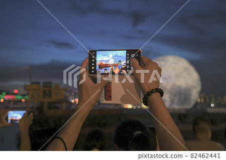 People pose for pictures against the backdrop of a huge glowing moon floating in the Kwun Tong typhoon shelter 21 Sept 2021 People pose for pictures against the backdrop of a huge glowing moon floating in the Kwun Tong typhoon shelter 21 Sept 2021 82462441
