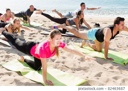 People practicing yoga on beach 82463687
