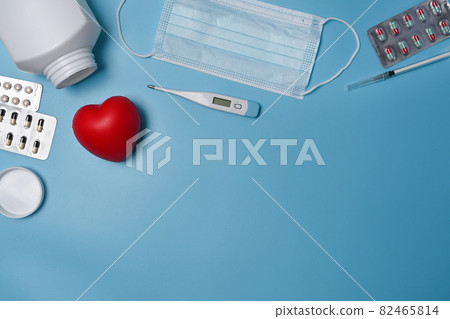 Above view protective mask, red heart, thermometer and medicine pills on blue background. Above view protective mask, red heart, thermometer and medicine pills on blue background. 82465814