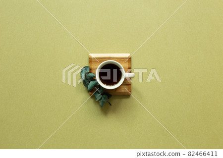 Cup of coffee with eucalyptus leaf on khaki background. top view, copy space 82466411