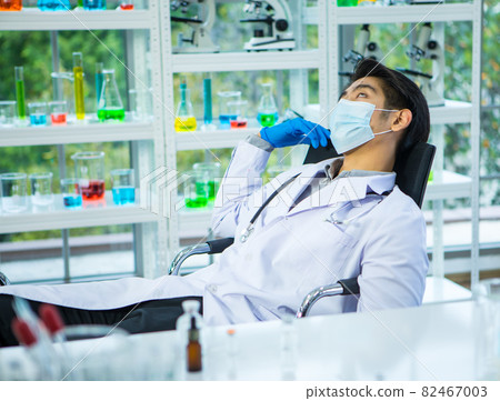 Doctor wearing protective mask feels tired during working for giving coronavirus vaccine to people, lay down and sleep on chair with exhausted gesture. Medical team hard work in outbreak concept Doctor wearing protective mask feels tired during working for giving coronavirus vaccine to people, lay down and sleep on chair with exhausted gesture. Medical team hard work in outbreak concept 82467003