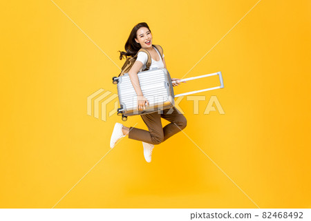 Energenic beautiful Asian woman tourist with luggage jumping in mid-air Energenic beautiful Asian woman tourist with luggage jumping in mid-air 82468492