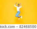 Energetic young African American woman jumping with hands pointing up 82468500