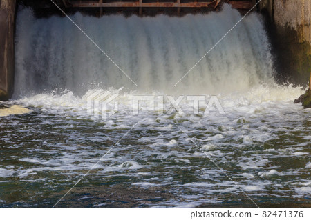 Flowing water with water spray from the open sluice gates of a small dam Flowing water with water spray from the open sluice gates of a small dam 82471376