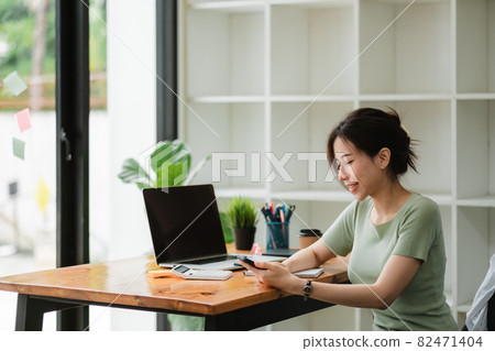 Happy asian woman using mobile phone at modern office 82471404