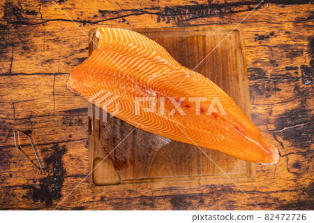 Large raw salmon fillet on a wooden board with fish bone pliers 82472726