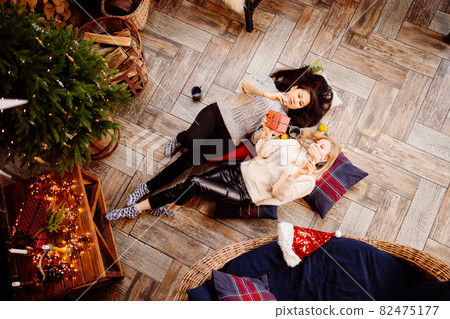 top view. cheerful girlfriends in the New Year's decorations in the fireplace top view. cheerful girlfriends in the New Year's decorations in the fireplace 82475177