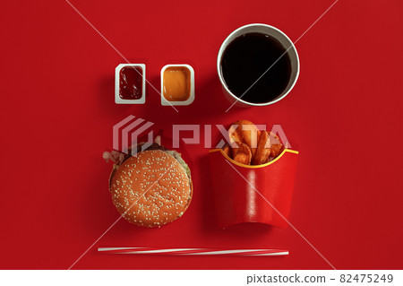 Fast food dish top view. Meat burger, potato chips and glass of drink on red background. Takeaway composition. 82475249