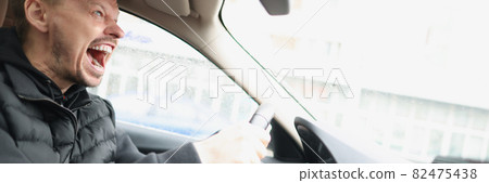 Angry screaming male driver driving car closeup Angry screaming male driver driving car closeup 82475438
