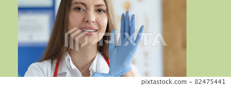 Portrait of female doctor putting on medical gloves Portrait of female doctor putting on medical gloves 82475441