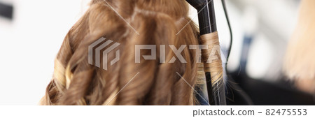Hairdresser makes evening hairstyle for woman in form of curls 82475553