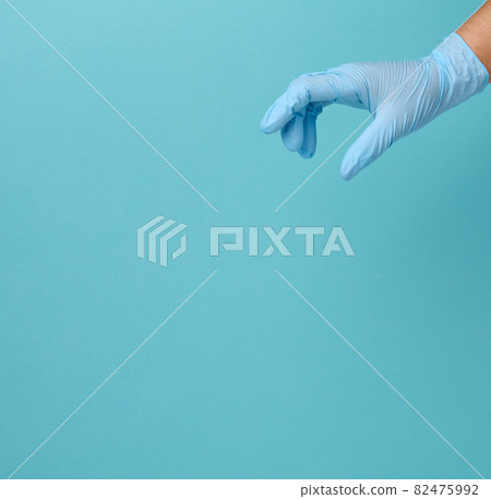 Doctor's hand in a blue medical glove holds an object on a blue background 82475992