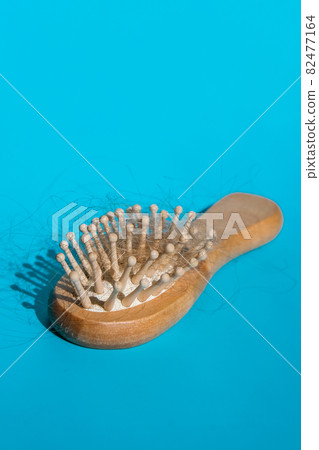 Blonde hair loss problem with hairbrush on blue background. Alopecia, hair problem, falling hair on brush healthy medical treatment concept. Blonde hair loss problem with hairbrush on blue background. Alopecia, hair problem, falling hair on brush healthy medical treatment concept. 82477164