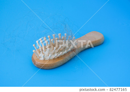 Blonde hair loss problem with hairbrush on blue background. Alopecia, hair problem, falling hair on brush healthy medical treatment concept. Blonde hair loss problem with hairbrush on blue background. Alopecia, hair problem, falling hair on brush healthy medical treatment concept. 82477165