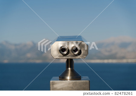 coin operated binoculars in front of mountains and sea 82478261