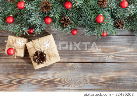 Christmas border with fir branches, red balls, cones on a wooden background. Christmas border with fir branches, red balls, cones on a wooden background. 82480208